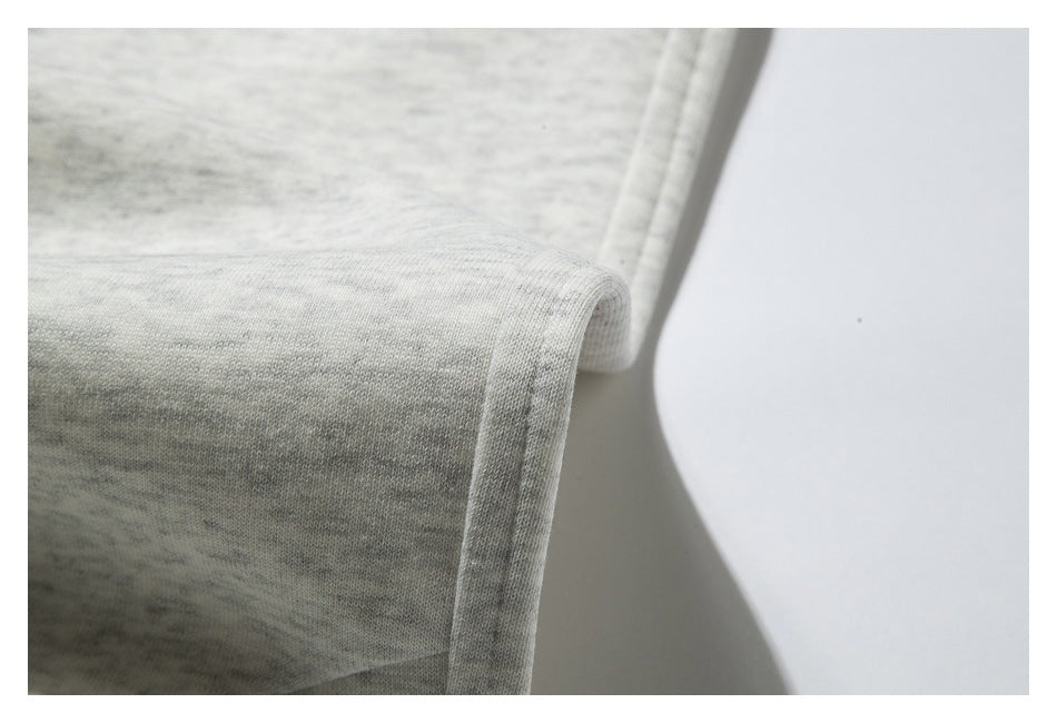 Close-up of the folded, stitched hem on light heather-gray sweatpants.
