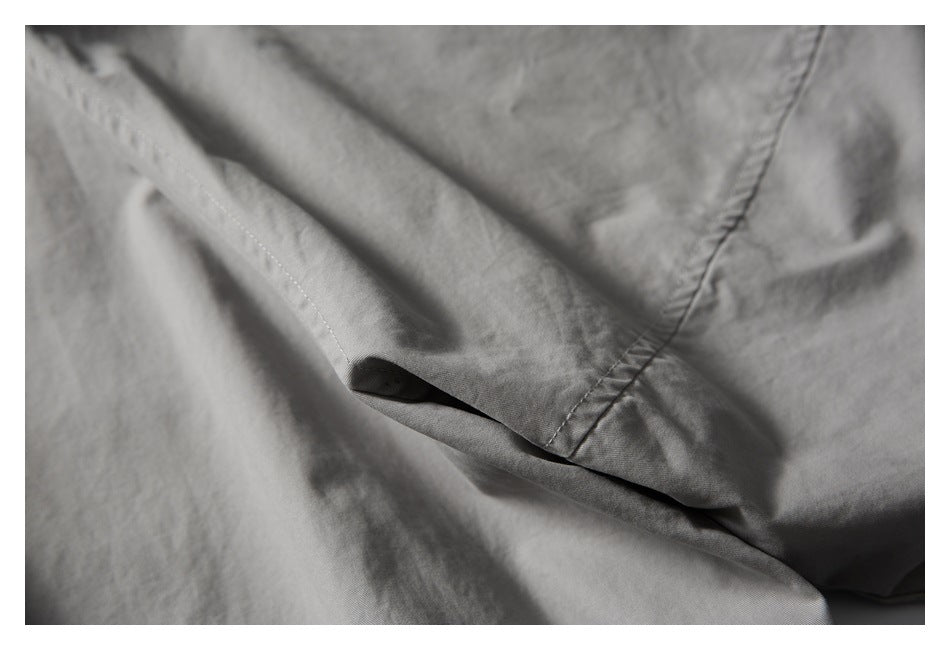 Close-up of a slit pocket opening and stitched seams on a light gray garment.