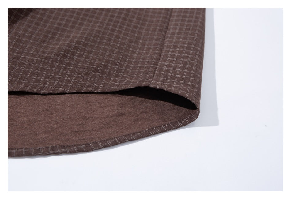 Close-up of the curved hem of a brown small-check shirt.
