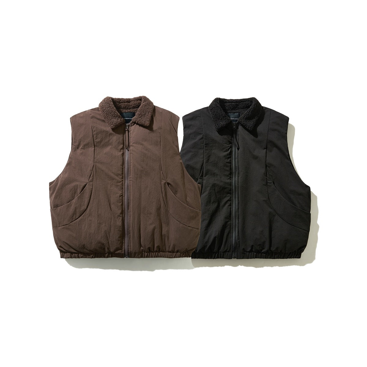 Front view of two sleeveless zip vests, one brown and one black, both with fleece collars and curved pockets.