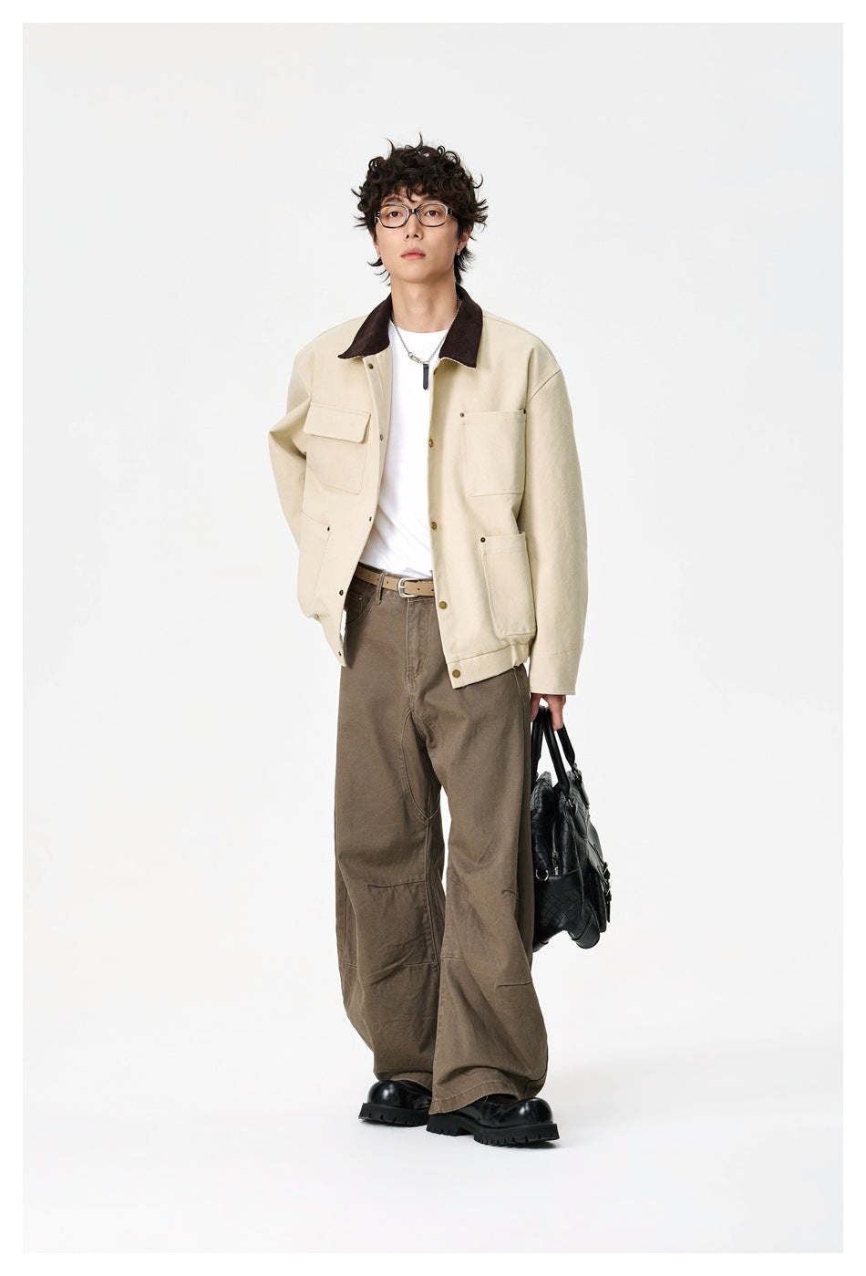 Full-length model wearing a cream, dark-collar jacket with wide brown trousers and black shoes.