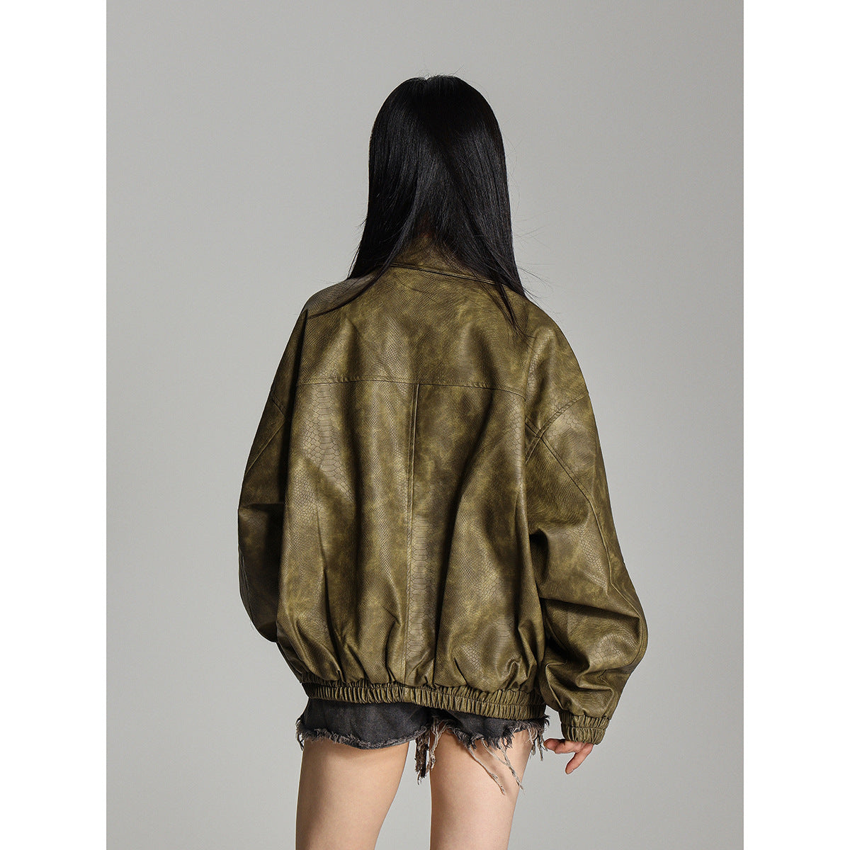 Back view of an oversized olive mottled jacket with a center seam and elastic hem and cuffs.