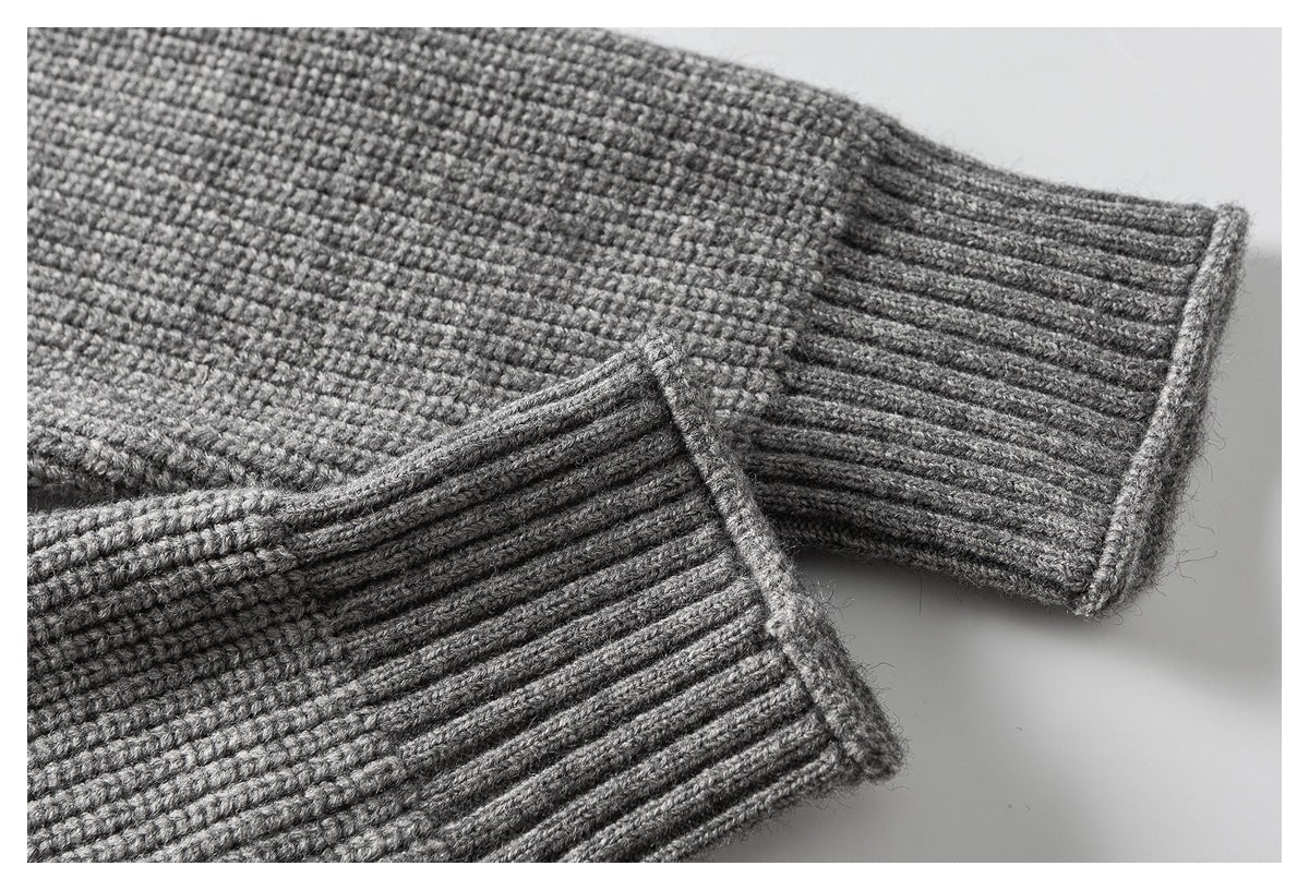 Close-up of a gray sweater sleeve showing the ribbed cuff and textured knit.