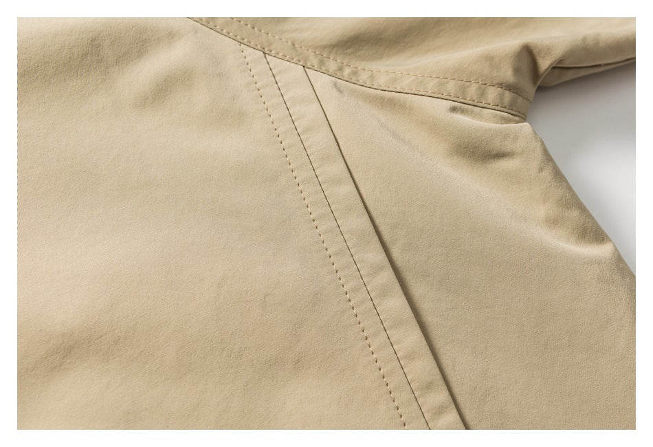 Close-up of beige fabric with a diagonal stitched seam and a narrow welt pocket.