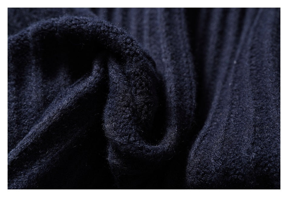 Close-up of the dark navy sweater's knit texture and folded sleeve cuff.