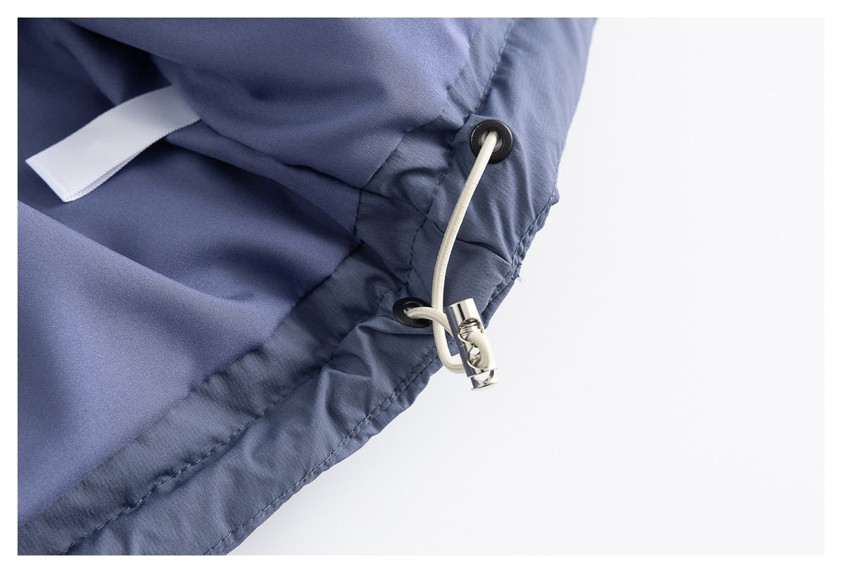 Close-up of a blue-gray jacket hem with an adjustable white drawcord and metal toggle.