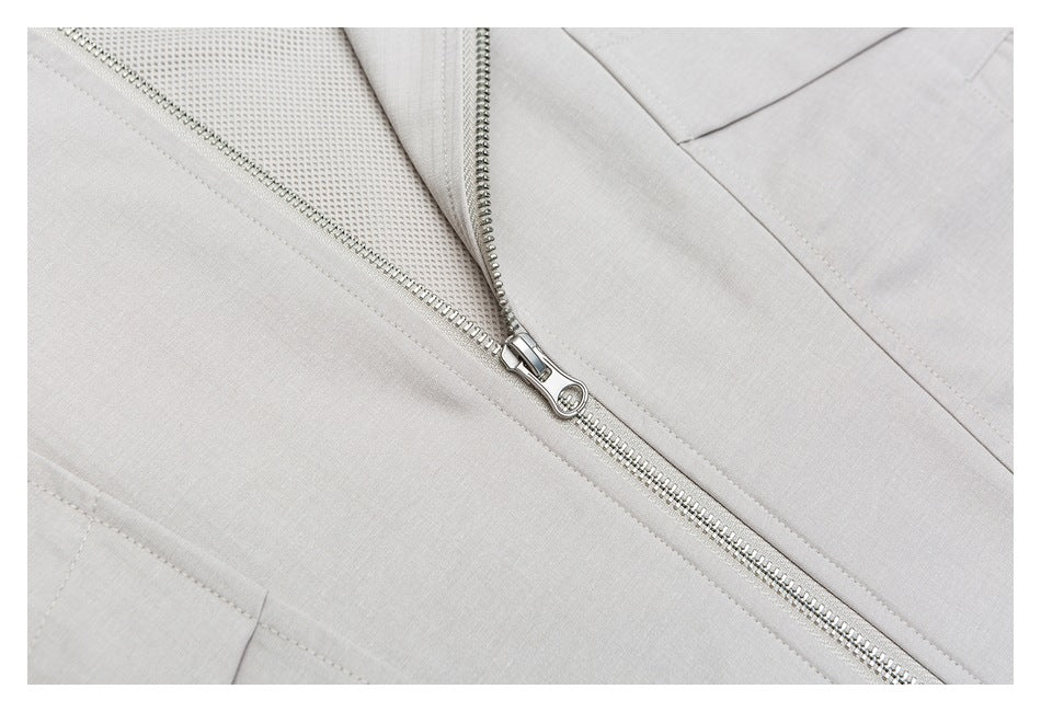 Close-up of a silver zipper on pale gray fabric, with mesh visible underneath.