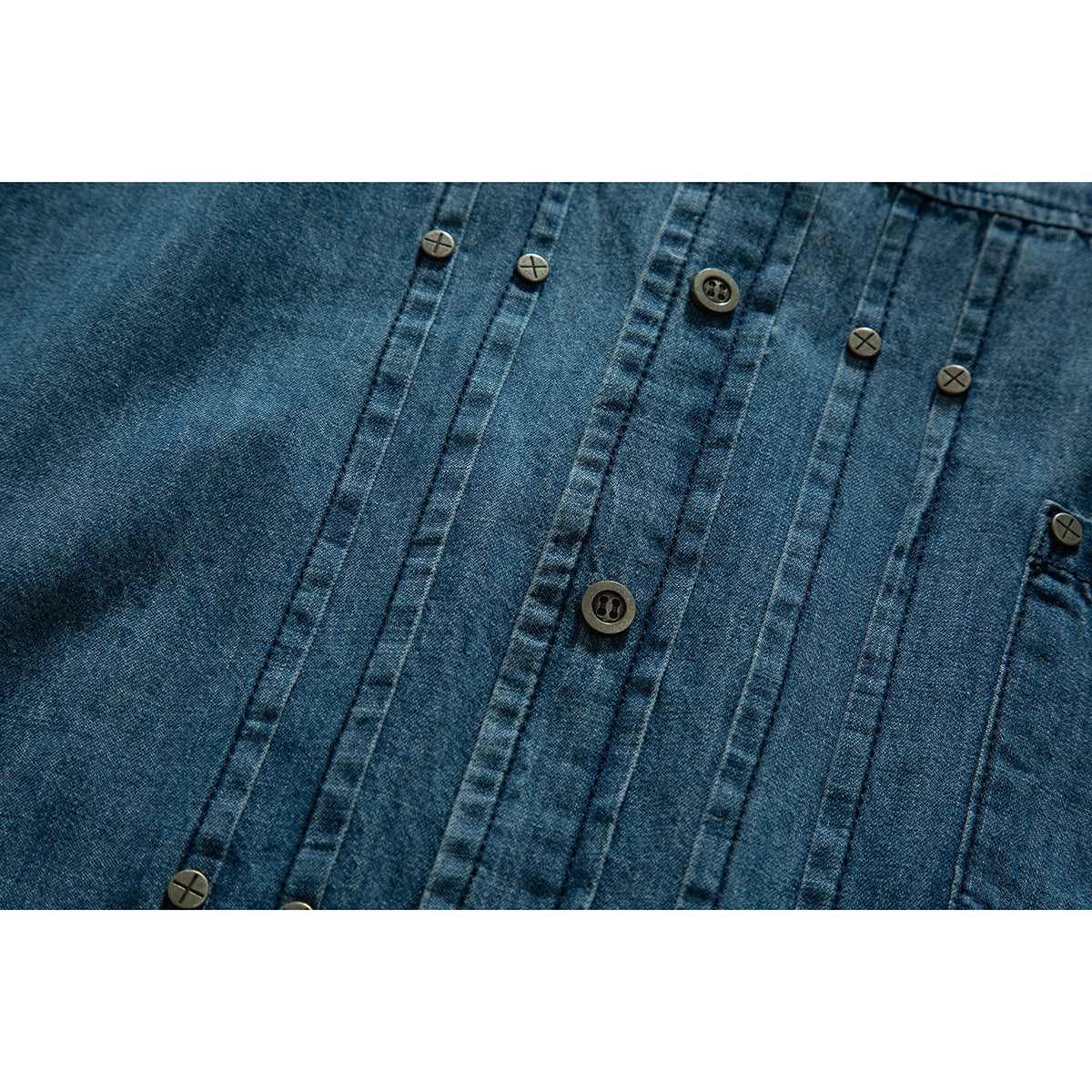 Close-up of a blue denim shirt front with vertical seams and contrasting buttons.