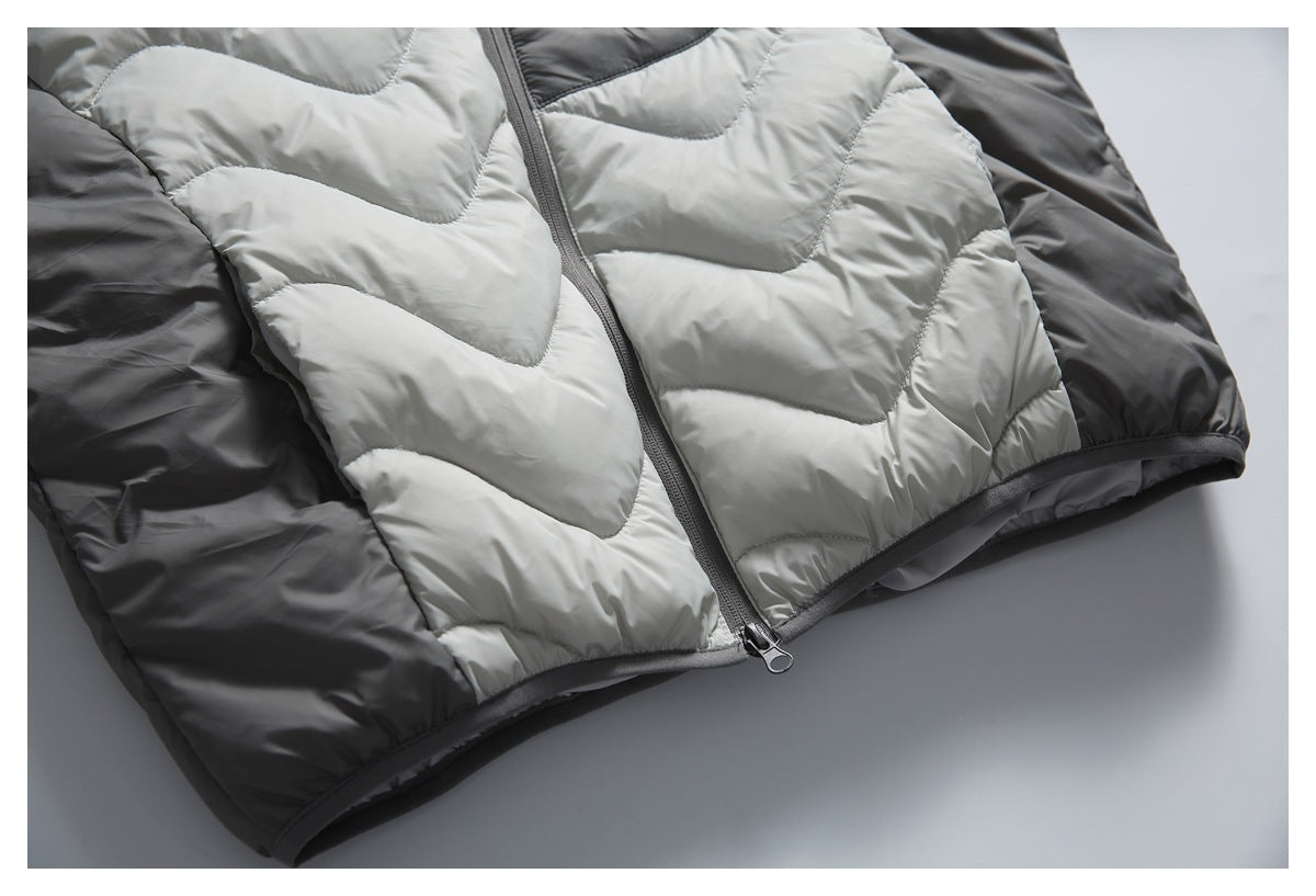 Partial flat lay of the jacket front, with light gray quilted panels, dark gray sleeves, and a center zipper.