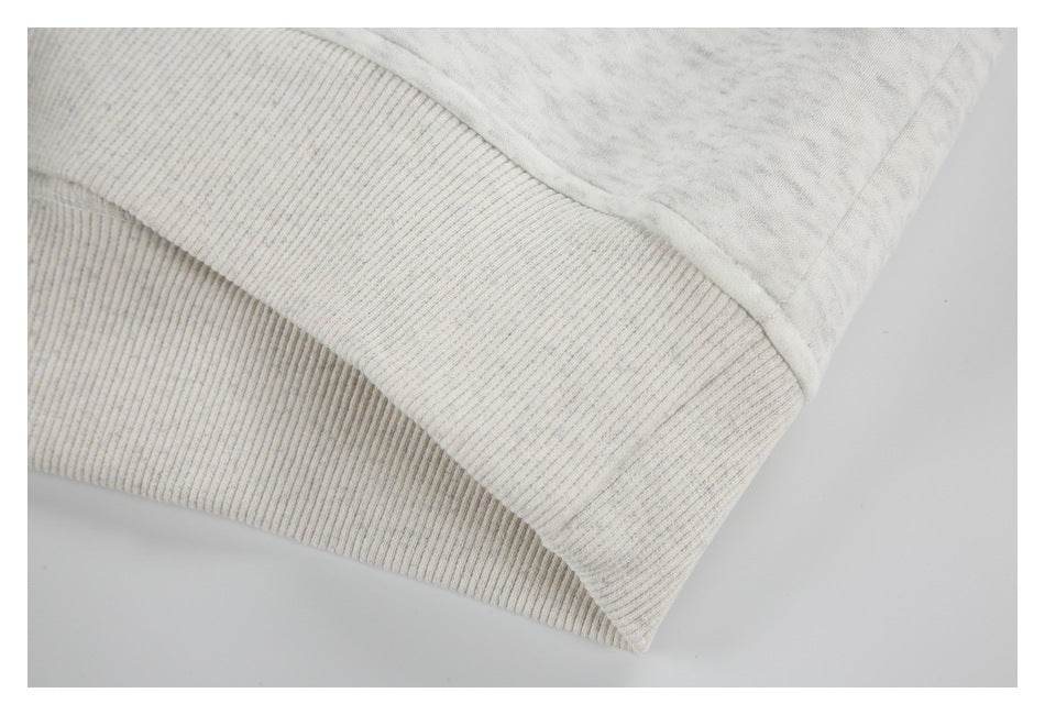 Close-up of the wide rib-knit hem on a light gray heather sweatshirt.
