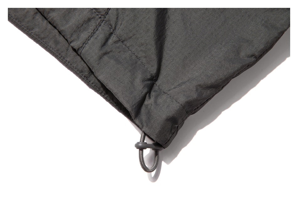 Close-up of the charcoal jacket's lower corner with a small elastic adjustment loop.