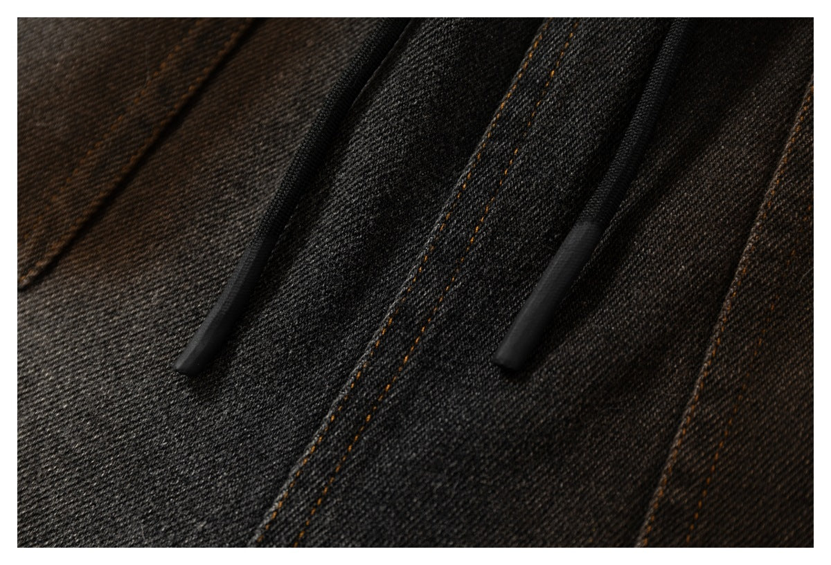 Close-up of black drawstrings against charcoal denim, with double-stitched seams in ochre thread.
