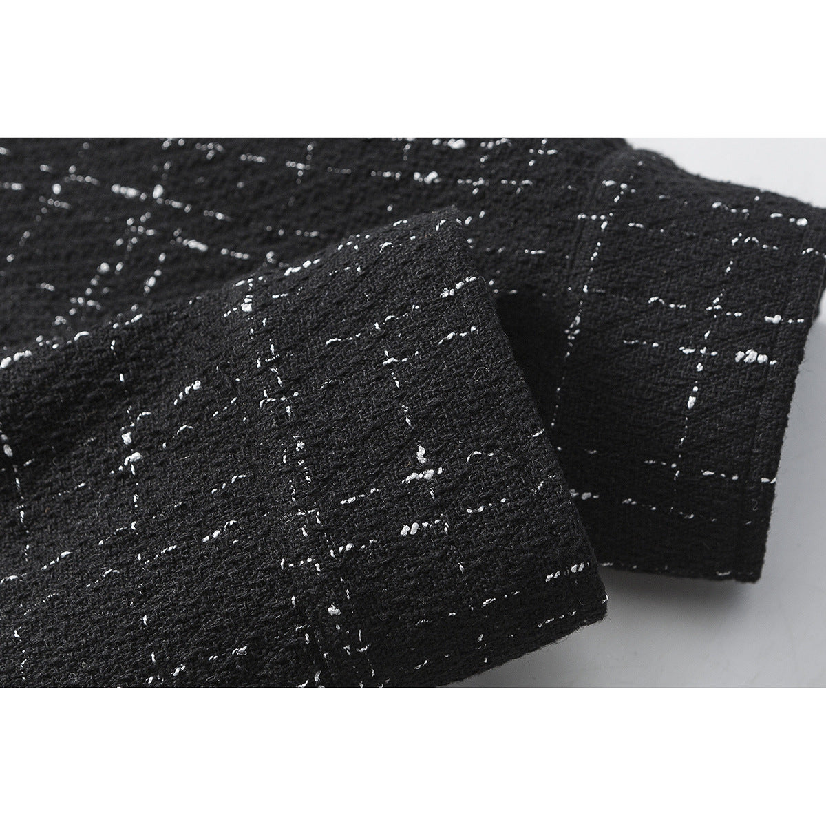 Close-up of the sleeve and cuff of a black shirt with a scattered white fleck pattern.