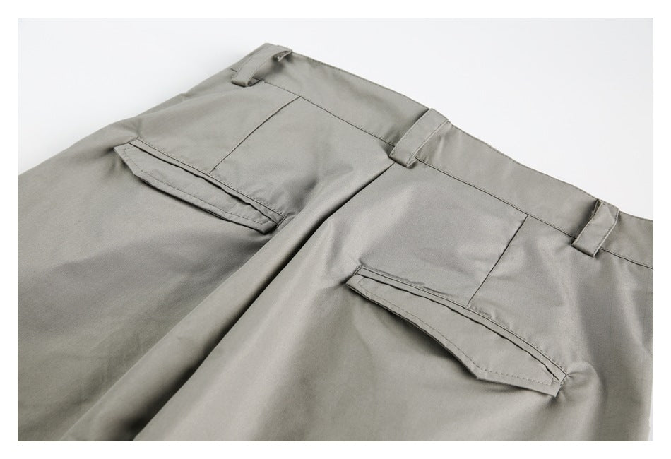 Cropped back view of taupe-gray trousers showing the waistband and two welt pockets.