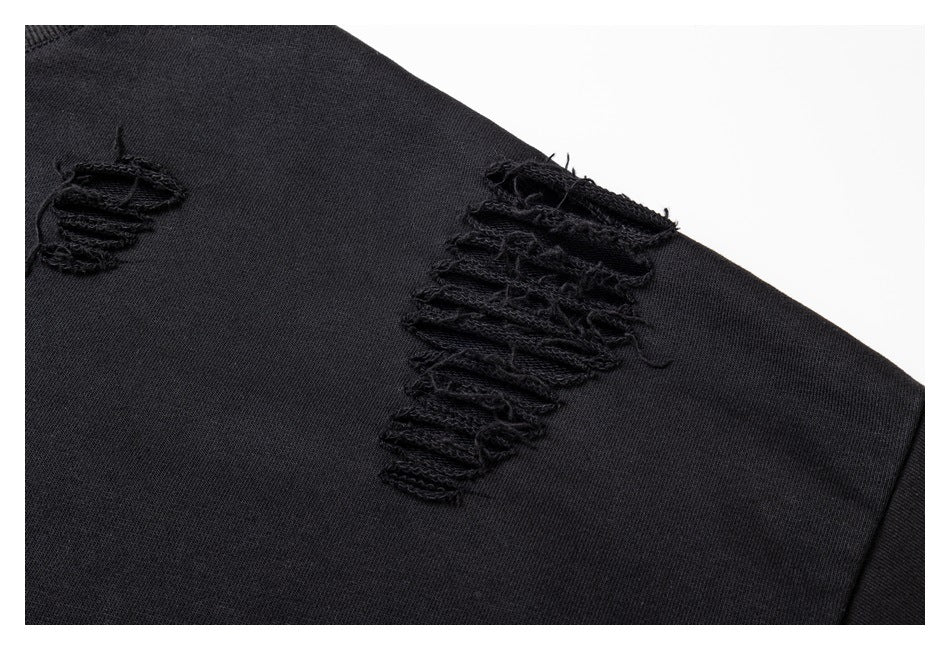 Close-up of a large frayed slash and a smaller distressed opening on the black sweatshirt sleeve.