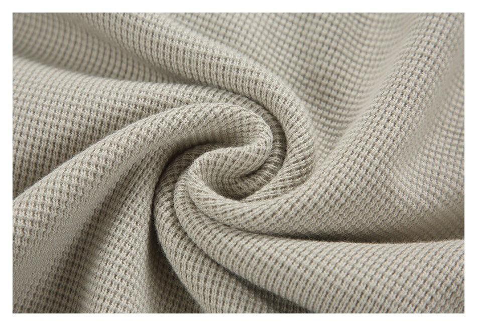 Close-up of light beige-gray textured knit fabric gathered into folds.