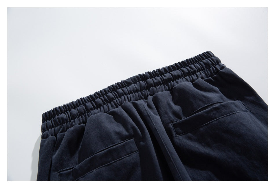 Close-up of dark navy pants showing a gathered elastic waistband and two pocket openings.