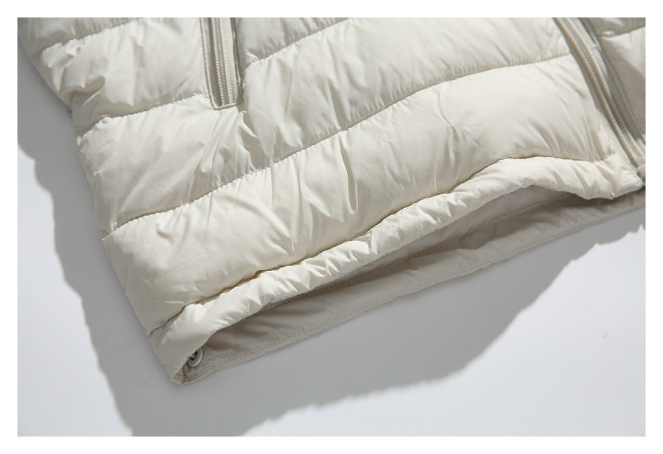 Close-up of the ivory jacket's padded lower hem and stitching, with parts of two pocket zippers visible.