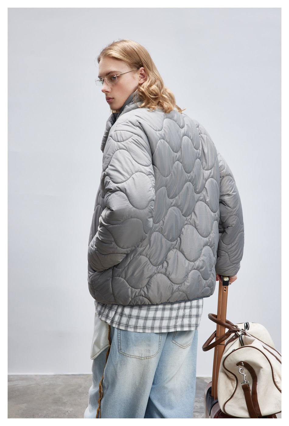 Rear three-quarter view showing the gray jacket's wave quilting and its loose fit.