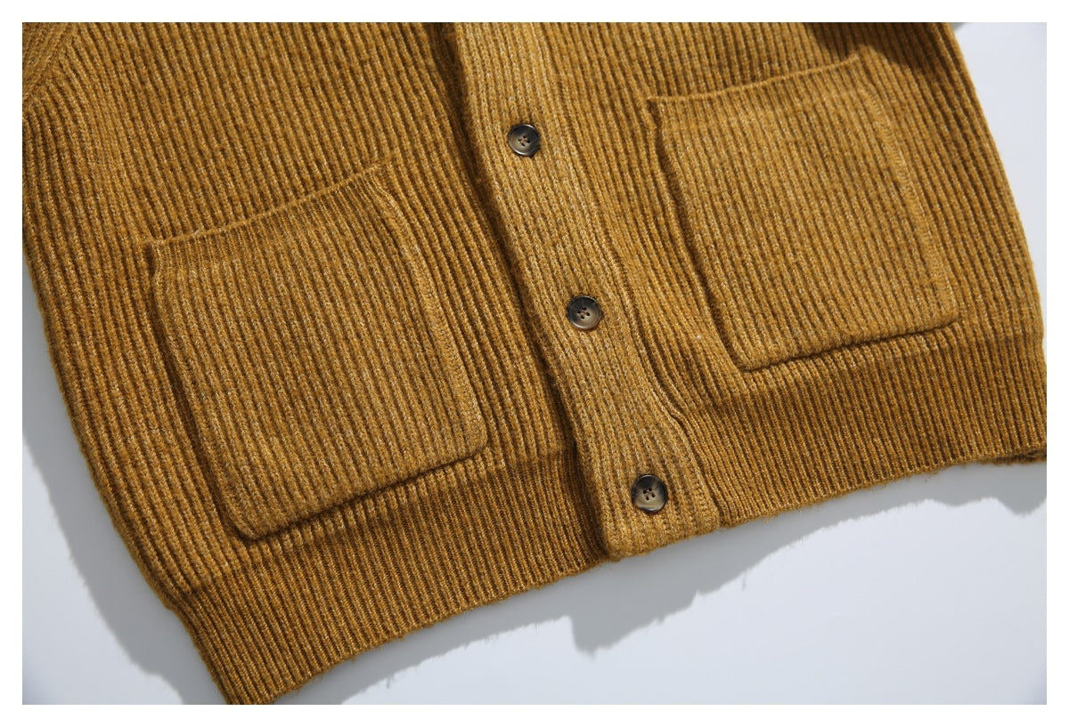 Partial flat-lay front of a mustard-brown ribbed cardigan with button placket, two patch pockets, and ribbed hem.