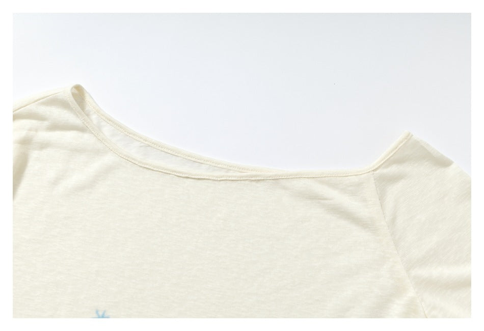 Close-up of the wide neckline and shoulder seam of an ivory long-sleeve shirt.