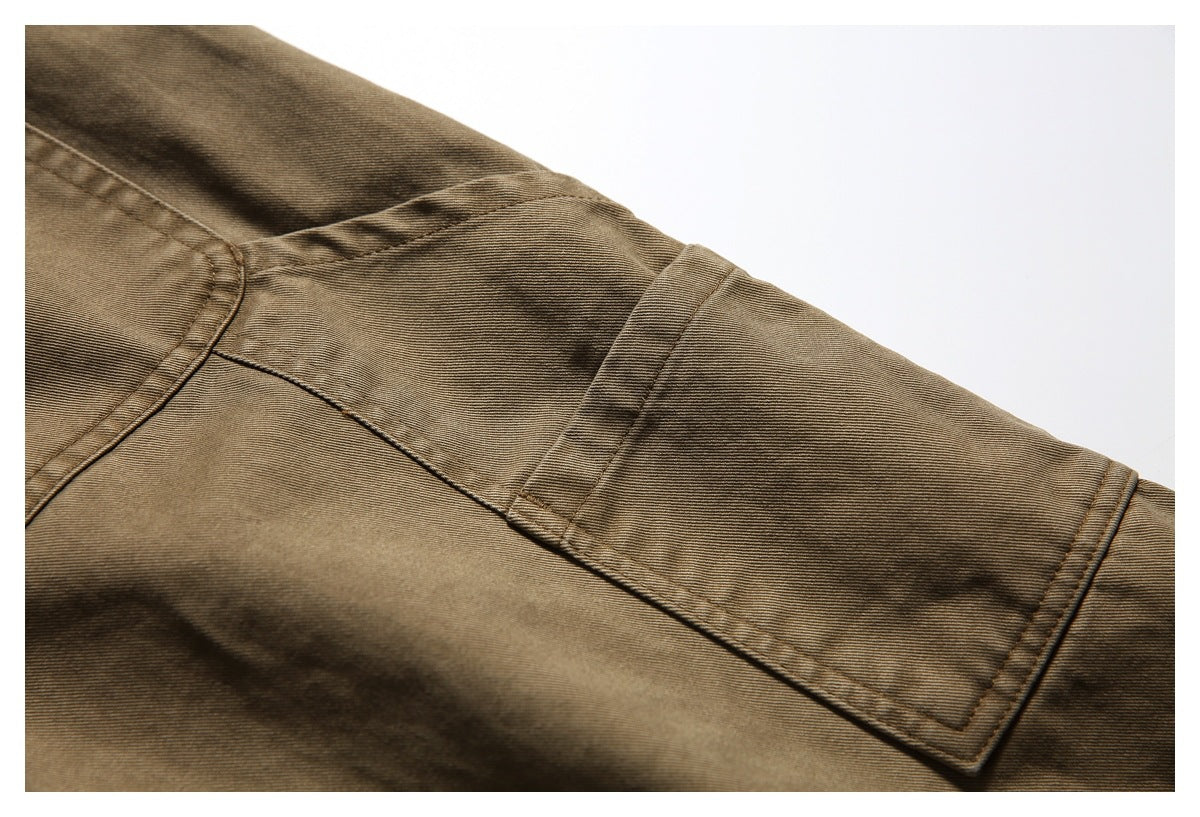 Close-up of brown pants showing stitched seams and a rectangular utility pocket panel.