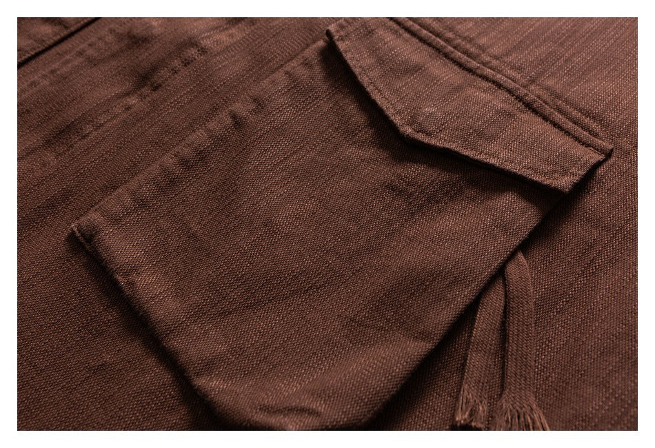 Close-up of a brown jacket's textured fabric, flap pocket, and stitched seams.