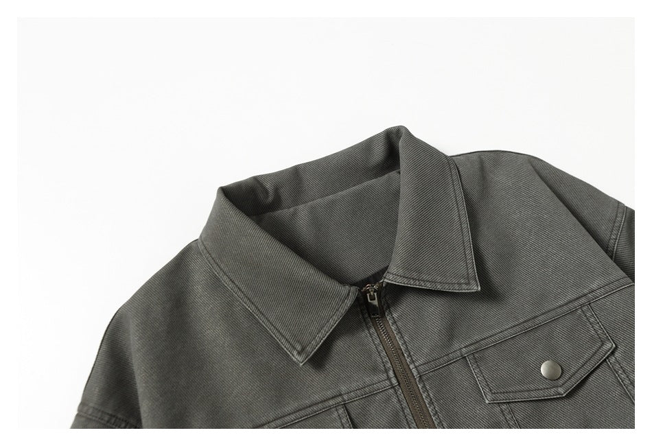 Charcoal gray jacket collar and upper front, showing a zipper and snap-flap chest pocket.