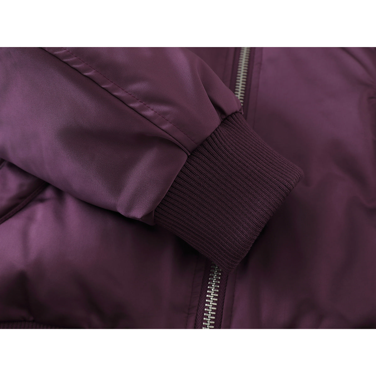 Close-up of a plum jacket’s ribbed sleeve cuff, with the front zipper visible behind it.