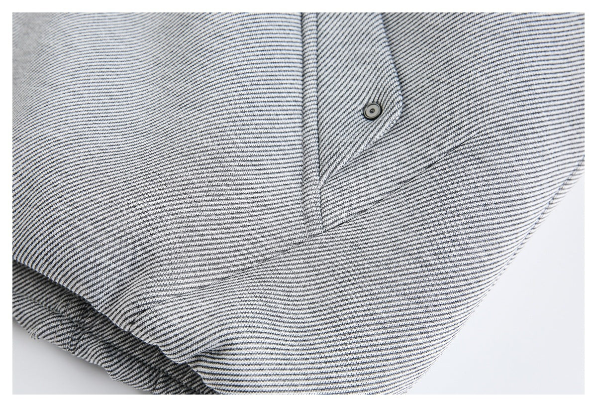 Close-up of striped jacket fabric and a small snap-fastened flap near the hem.