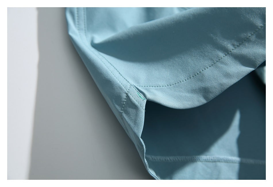 Close-up showing the folded hem, stitching, and small turquoise bartack on light blue shorts.