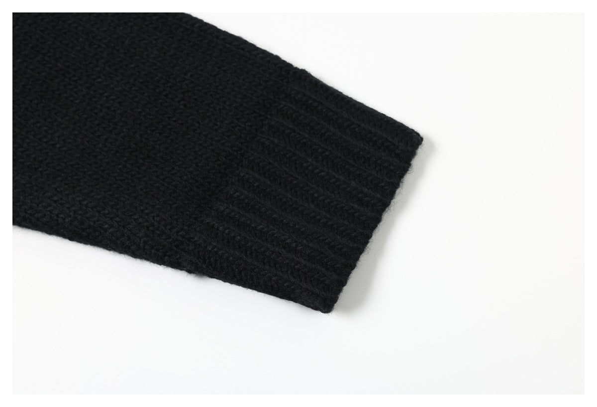 Close-up of the cuff and textured knit on a black garment against a white background.