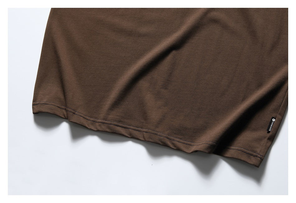 Close-up of the brown T-shirt's double-stitched hem and small black side tag.