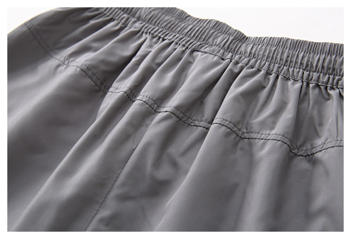 Close-up of gray shorts showing a gathered elastic waistband and stitched panel seams.