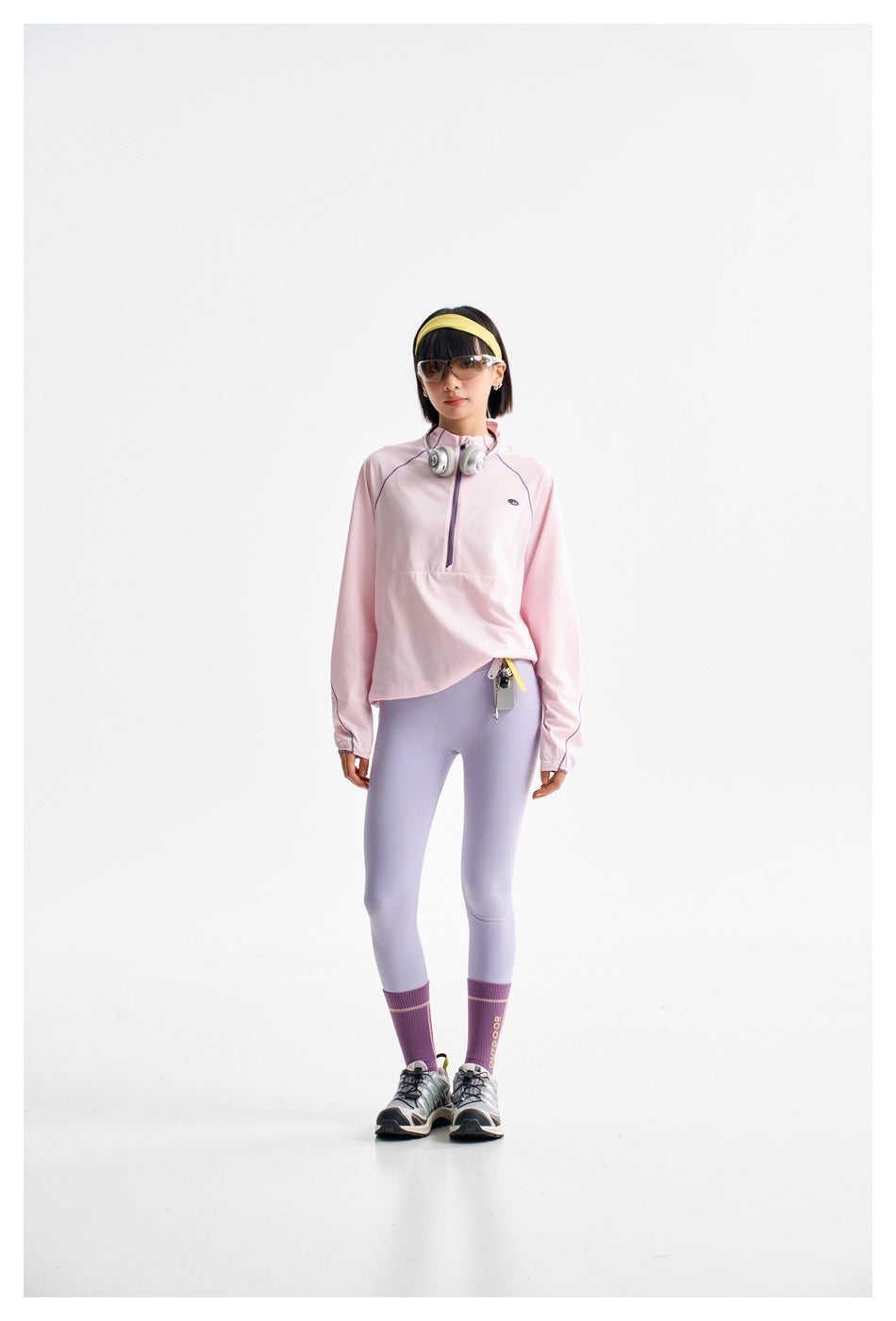 Model wearing a pale pink half-zip top with lavender piping and light lavender leggings.