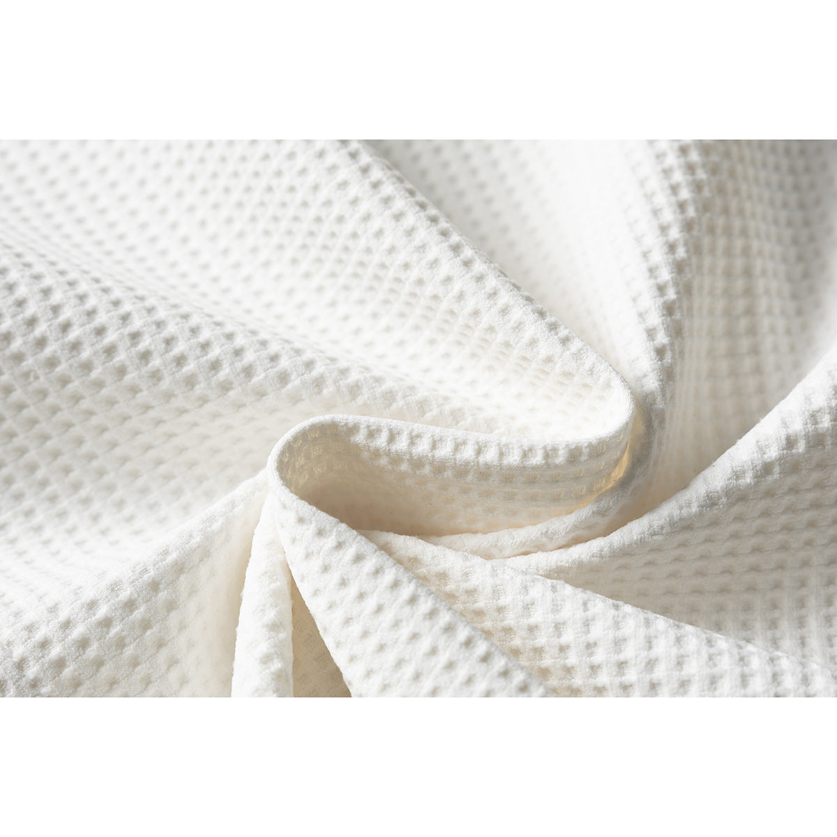 Close-up of off-white textured fabric folded to show its raised waffle-like surface.