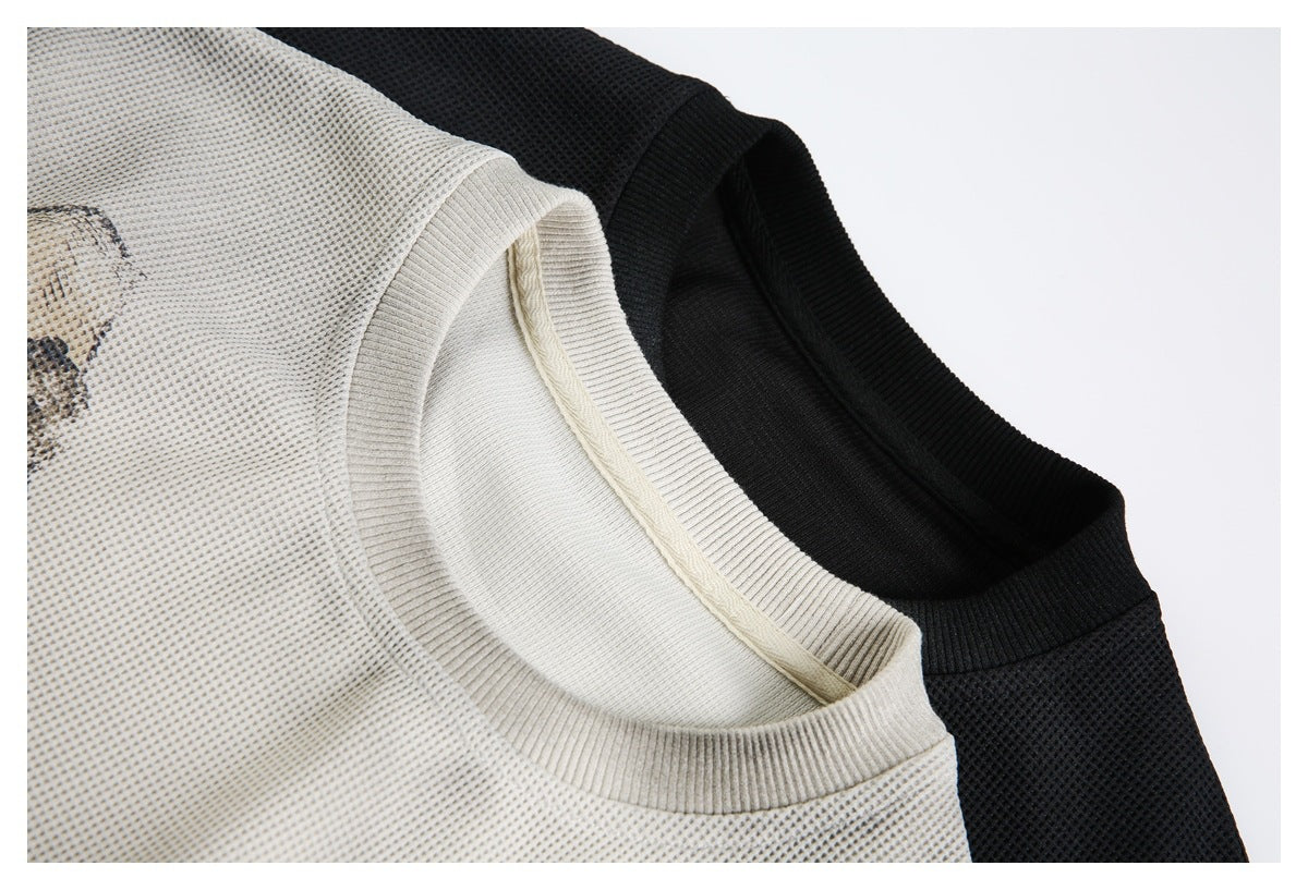 Close-up of cream and black textured knit tops showing their ribbed crew necklines.