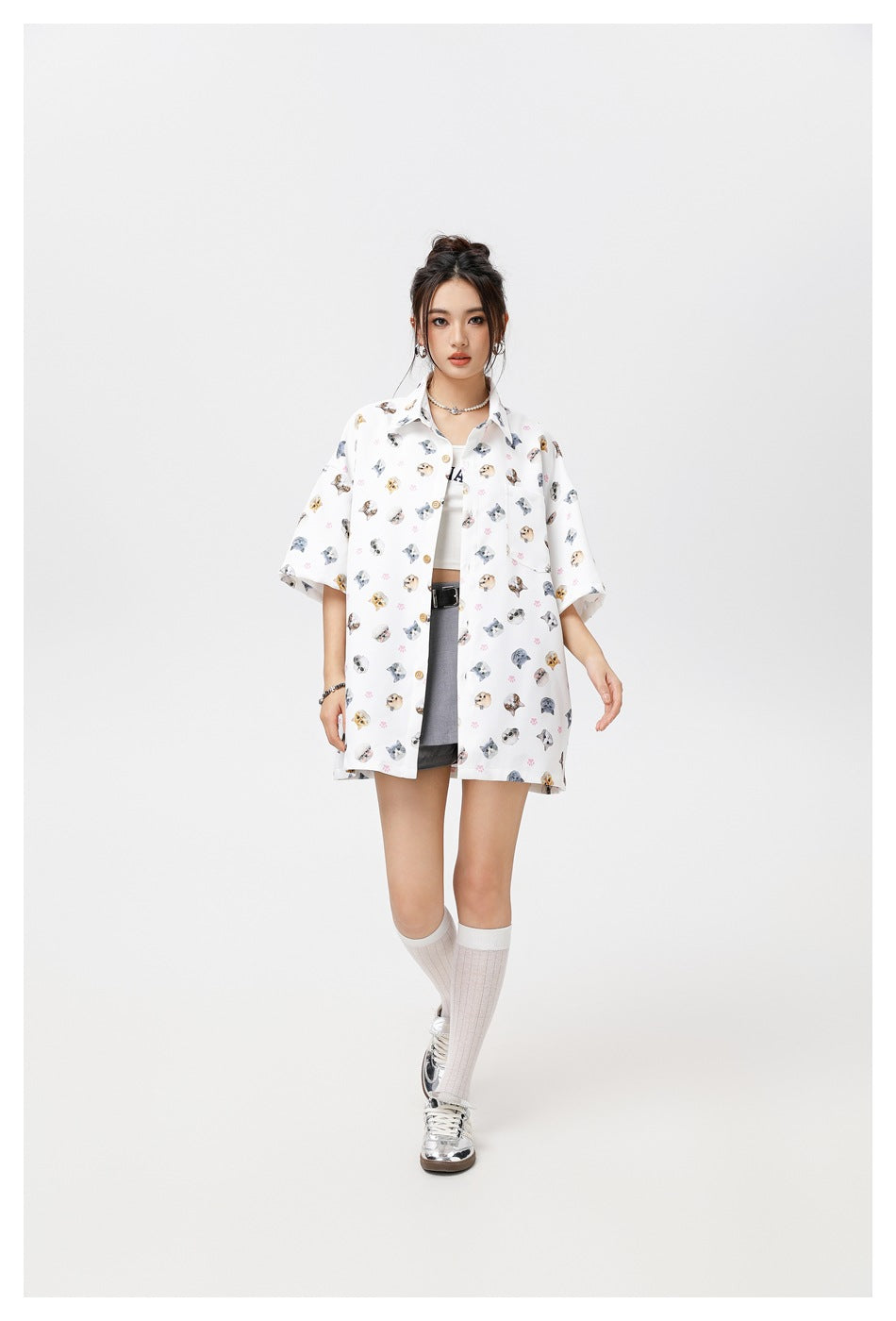 Model wearing the white cat print short-sleeve shirt open over a white top and gray skirt, with knee socks