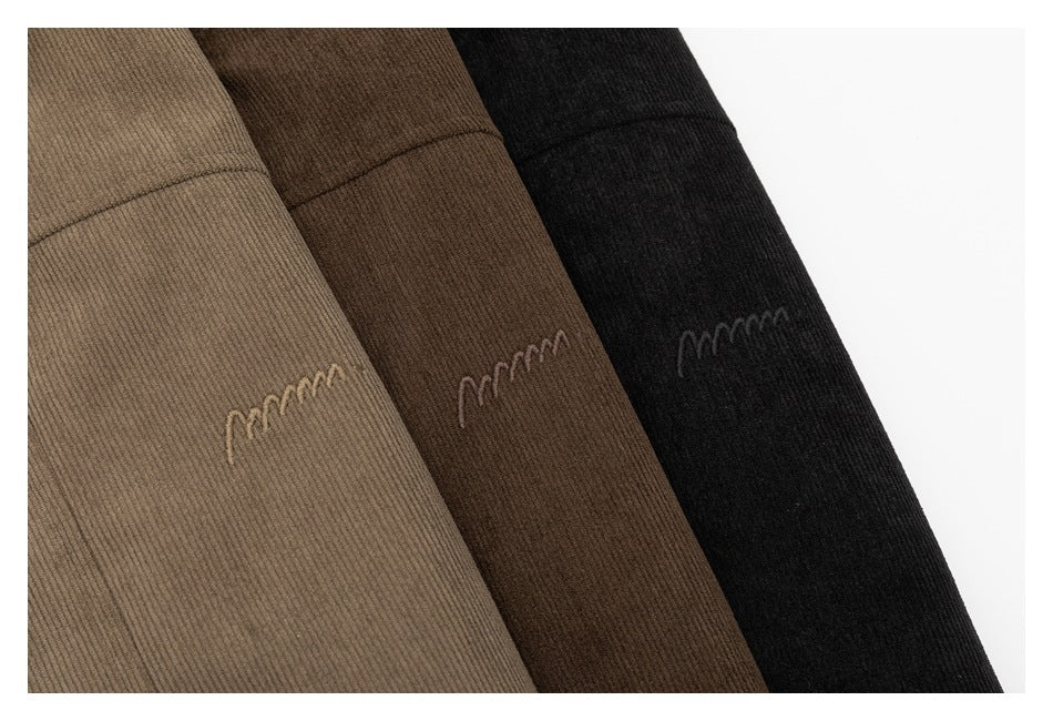 Close-up of taupe, dark brown, and black jacket fabric with small embroidered motifs.