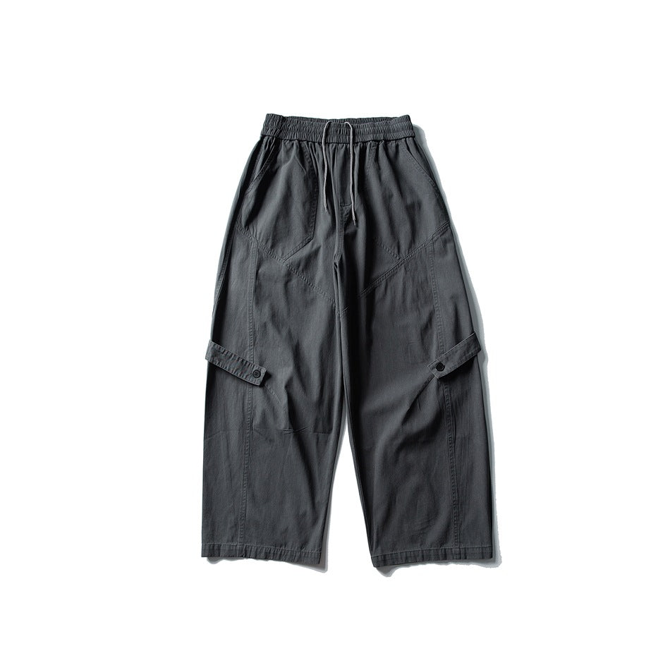 Dark gray wide-leg pants flat lay with drawstring elastic waist, diagonal seams and buttoned leg tabs