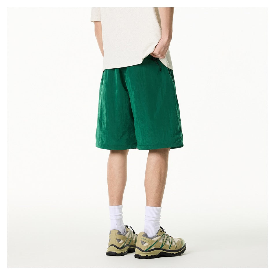 Cropped model showing the back of emerald green shorts with a light T-shirt and trail shoes.