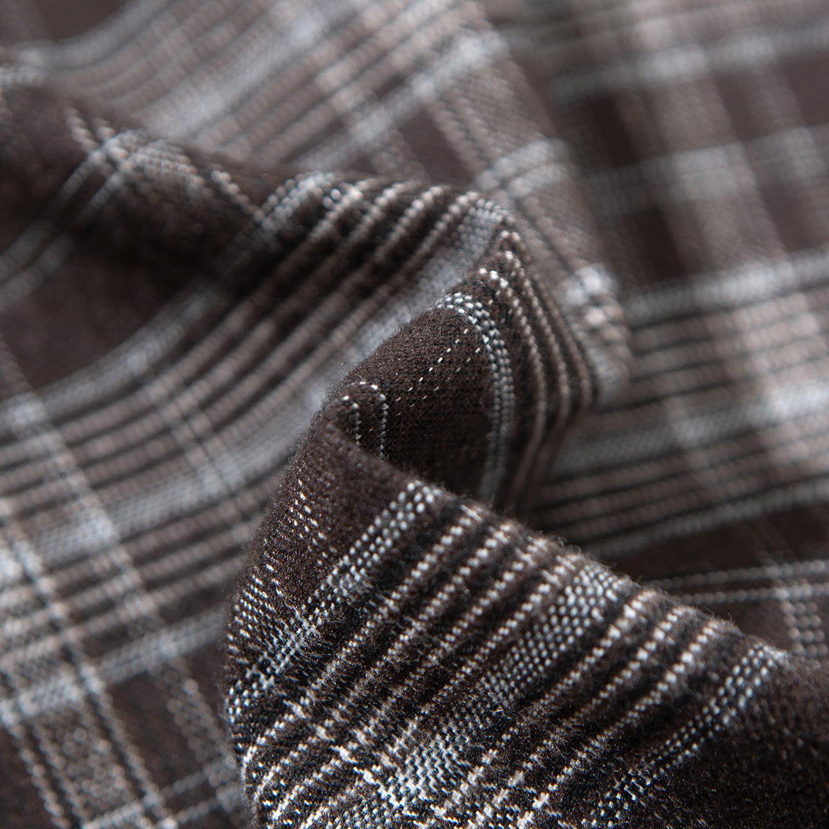 Macro view of brown and gray plaid shirt fabric and a folded seam.