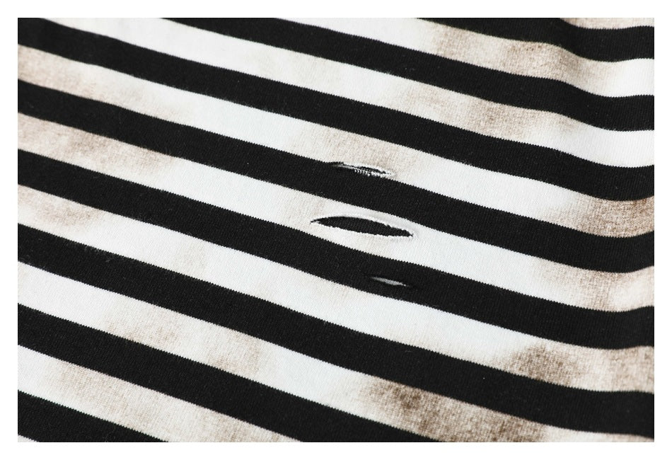 Close-up of black-and-cream stripes with faded discoloration and several small distressed slits.