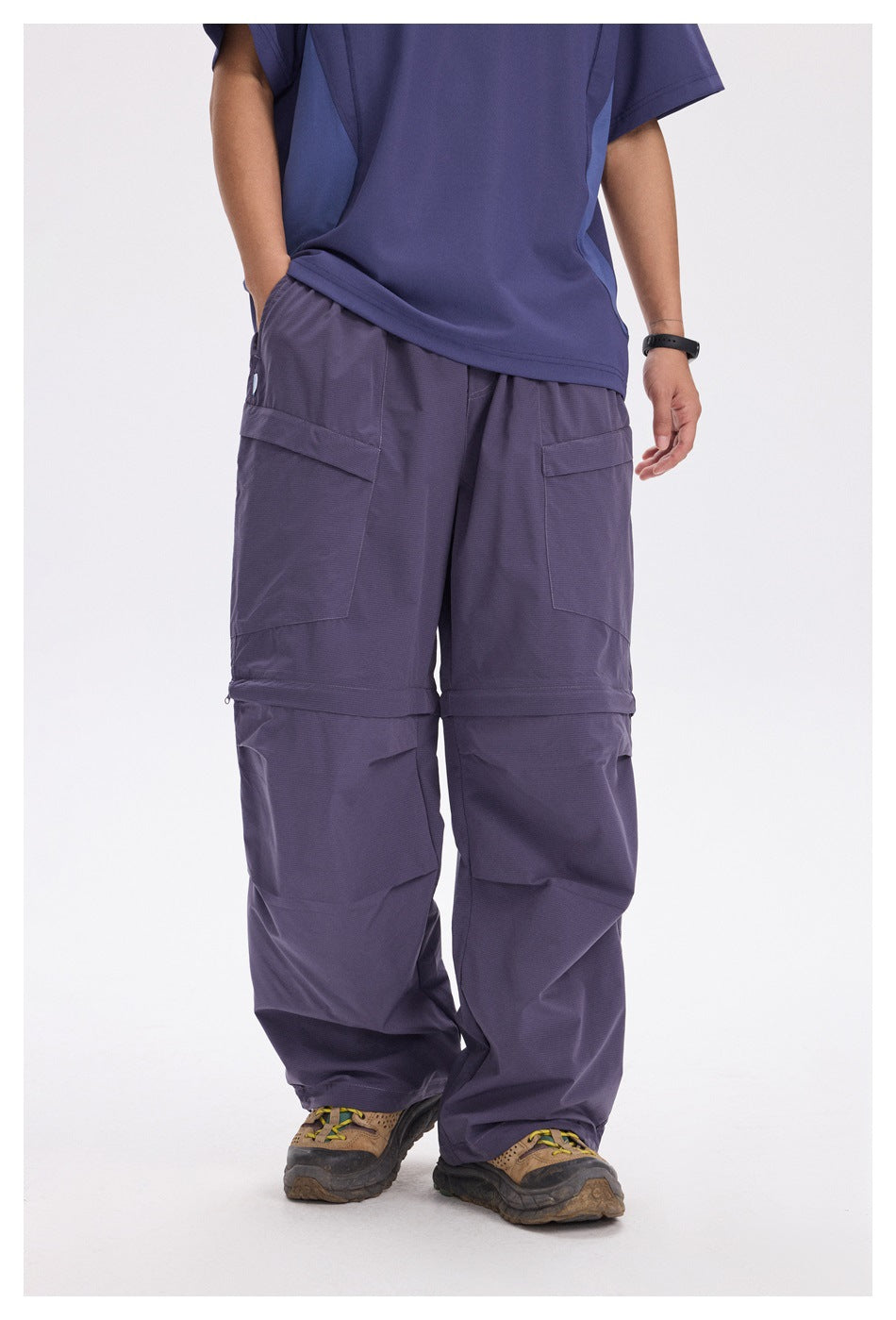 Front view of a person wearing loose purple cargo pants with large thigh pockets and knee seams.