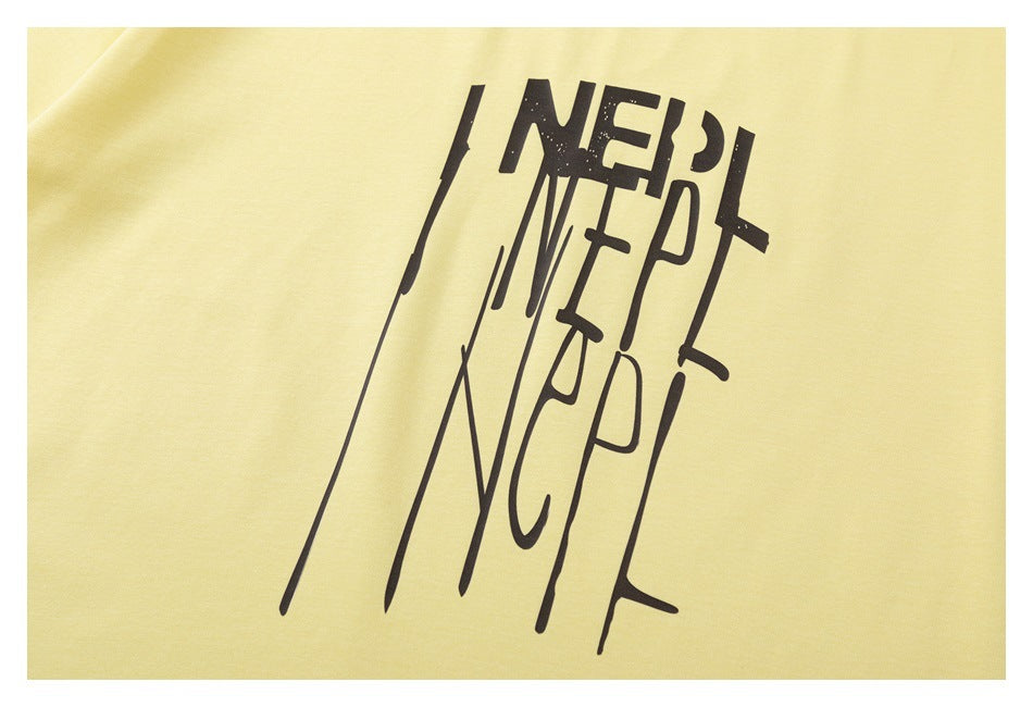 Close-up of oversized black stylized lettering printed on pale yellow T-shirt fabric.