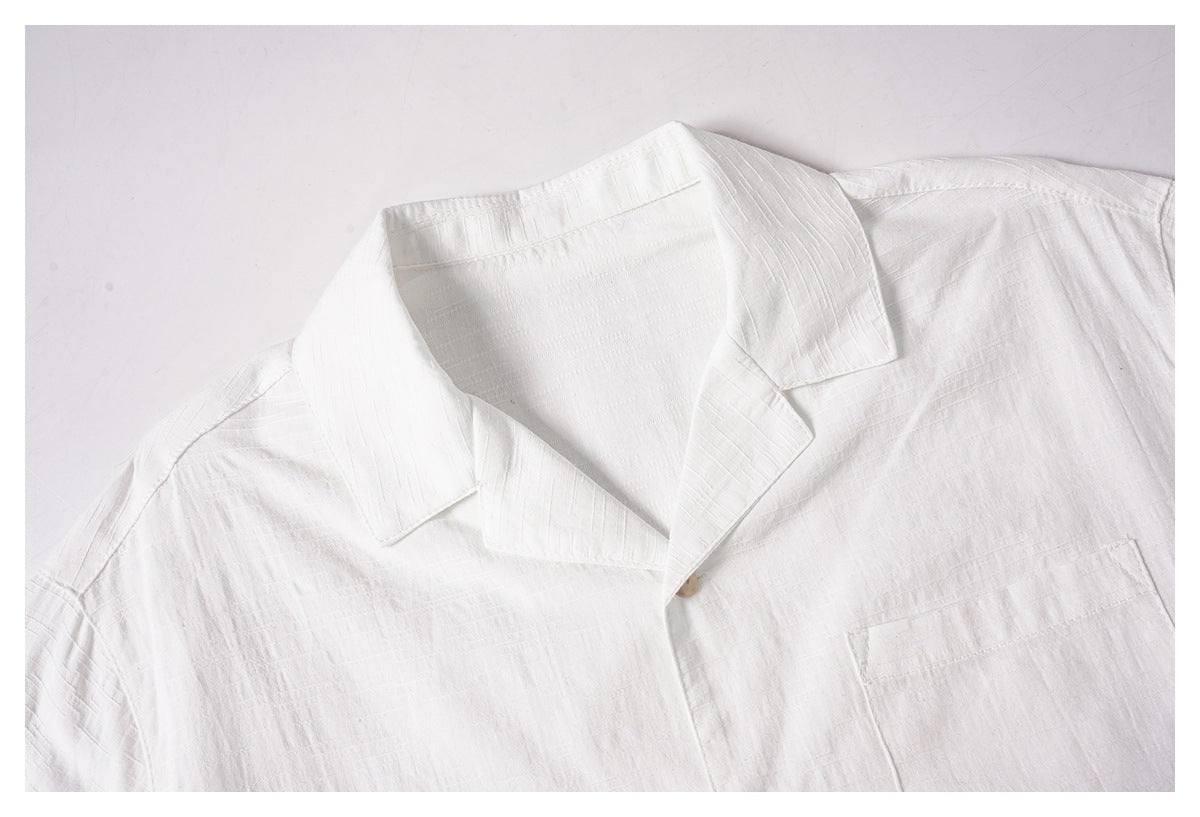 Close-up of a white shirt's open collar, front, and chest pocket.