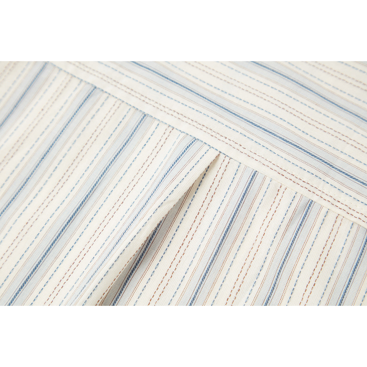 Close-up of stitched ivory shirt fabric with fine blue and brown stripes.