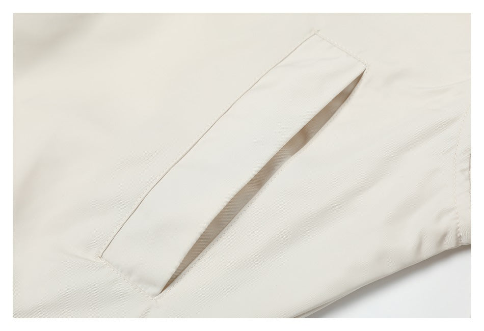 Close-up of a diagonal welt pocket on the ivory jacket.