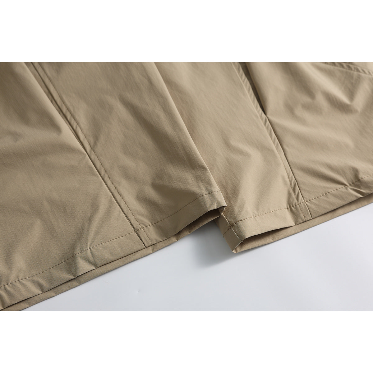Close-up of tan wide-leg pants showing the stitched hems and lower-leg seams.