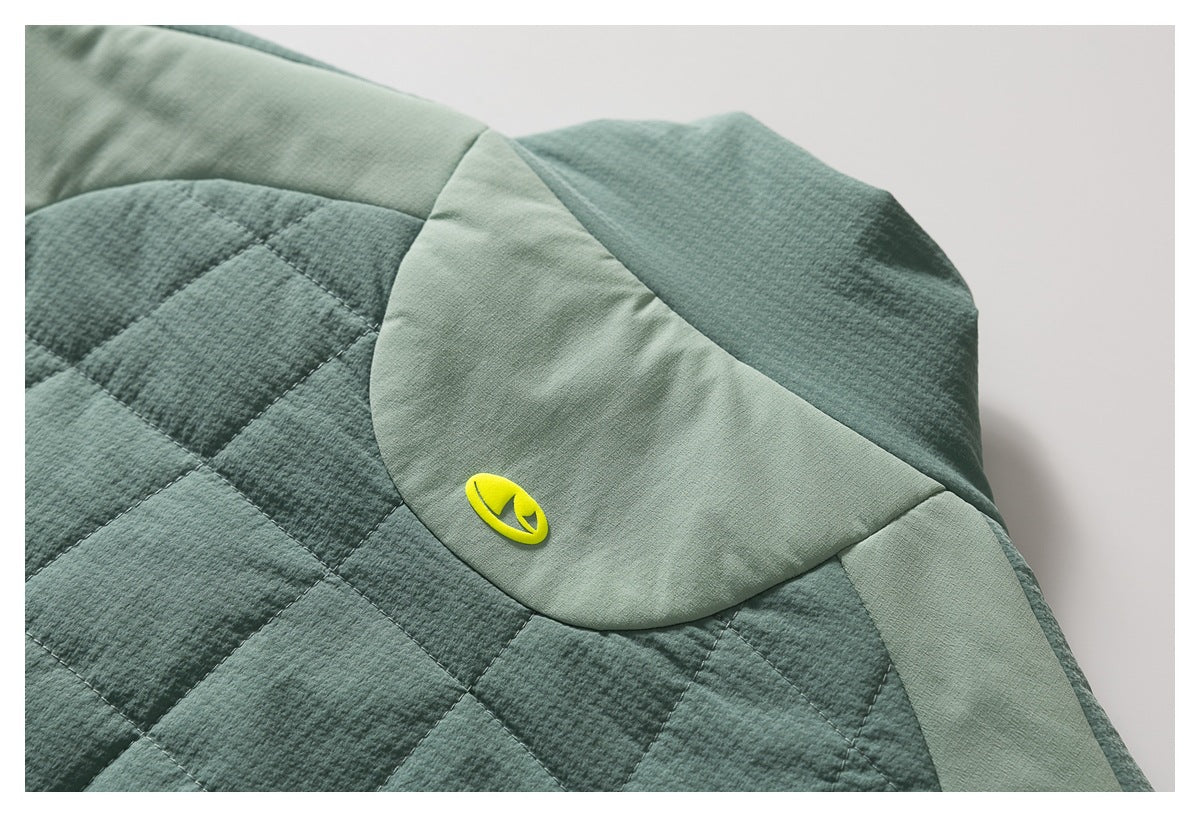 Close-up of a sage green quilted garment with a bright yellow emblem on a lighter green panel.